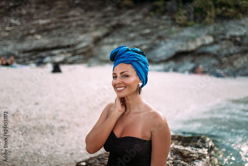 Fototapeta Naklejka Na Ścianę i Meble -  Outdoor portrait of beautiful woman with headscarf enjoying on the rocky beach.
