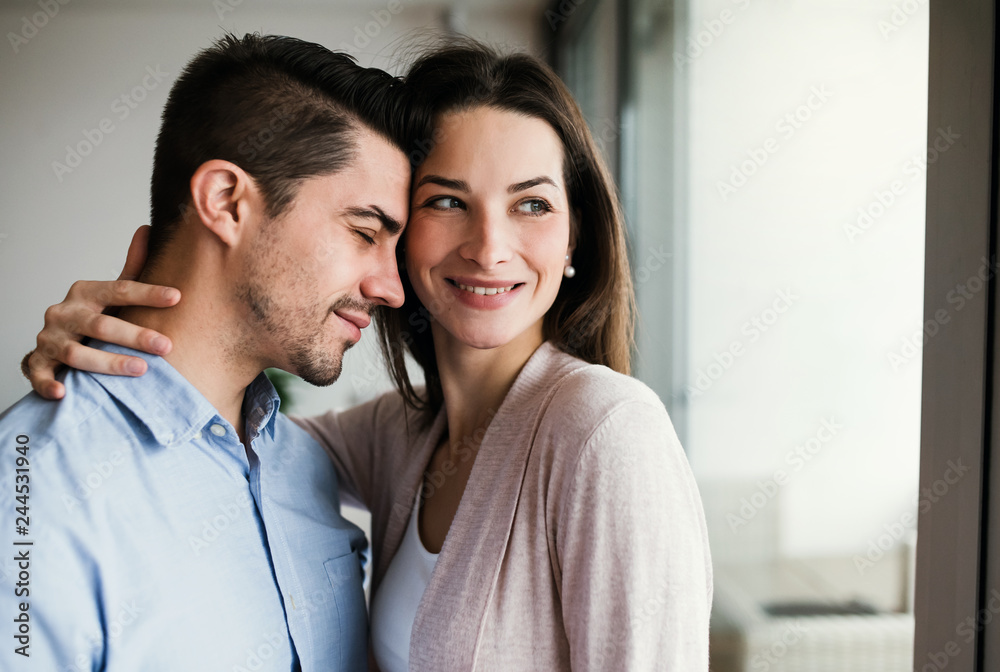 Young couple in love standing by the window at home, hugging. Copy space. Young couple in love standing by the window at home, hugging. Copy space.