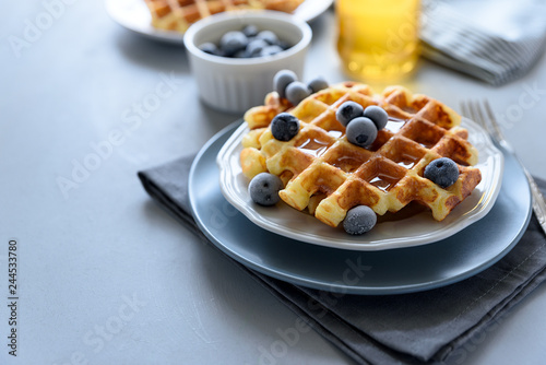 Belgian waffles with blueberries and honey on gray wooden background. Homemade healthy breakfast. Selective focus