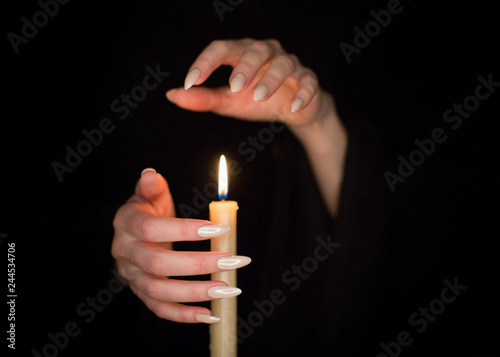 Foto Candle and female witch hands with sharp pearl nails
