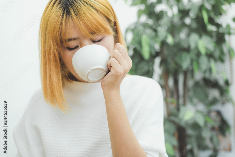 Attractive beautiful asian woman enjoying warm coffee in the kitchen at her home. Asian female wearing comfortable sweater holding a cup of coffee. lifestyle asia woman at home concept. Attractive beautiful asian woman enjoying warm coffee in the kitchen at her home. Asian female wearing comfortable sweater holding a cup of coffee. lifestyle asia woman at home concept.