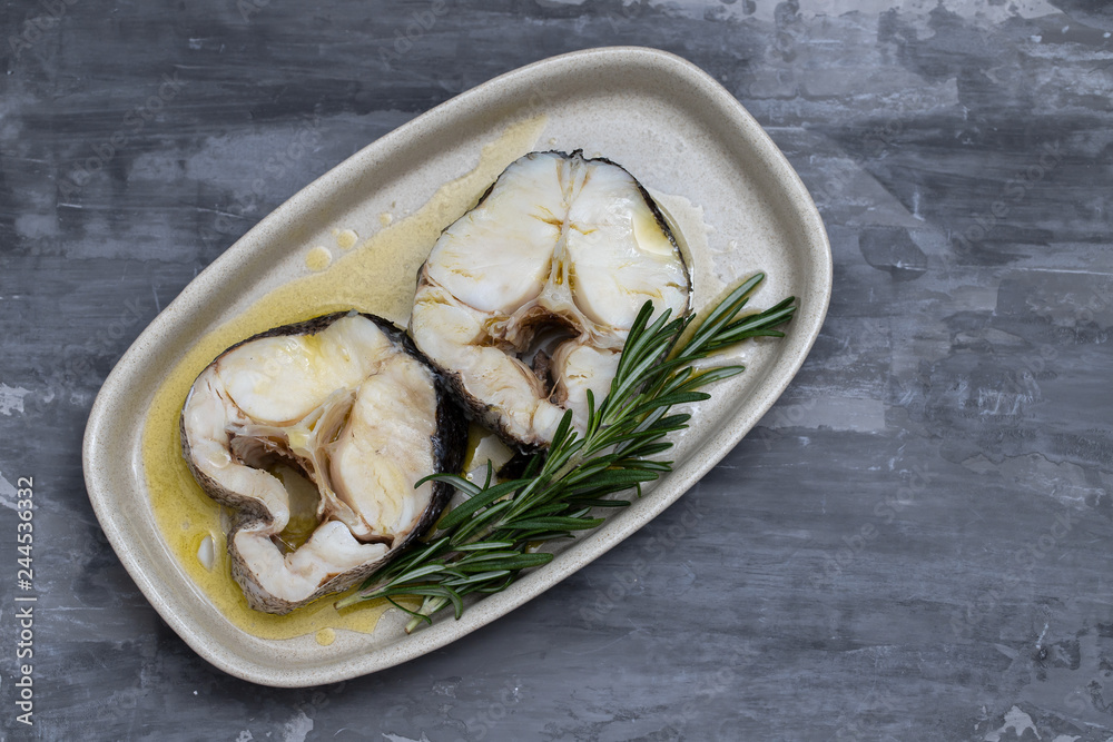 boiled fish with olive oil and rosemary in dish