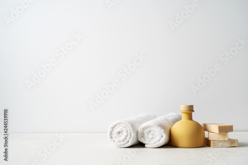 Spa concept: beautiful ceramic bottle, handmade organic soap, white towels and on concrete light surface with copy space.