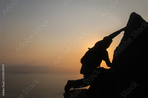 Silhouette of man climbing rock  Photographer on the mountain at sunrise
