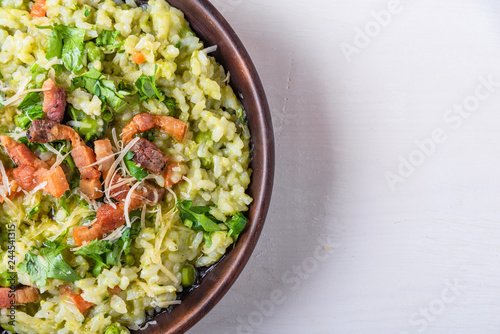 Traditional Italian risotto with peas, carrots and fried bacon, pancetta in rustic style, close-up, copy space for recipe