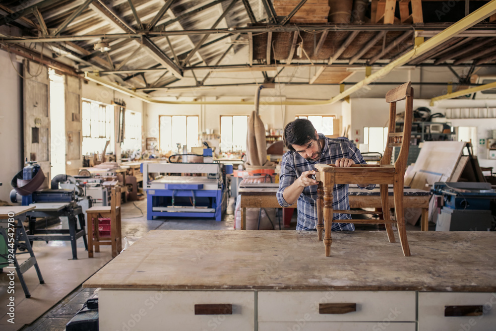 Furniture maker sanding a chair on his workshop table