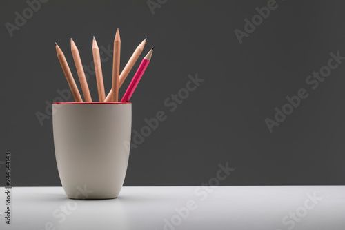 Pink pencil in cup standout from wooden pencil