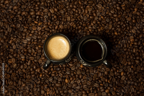 A cup of black coffee with milk standing on coffee beans. A healthy breakfast concept.