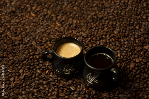 A cup of black coffee with milk standing on coffee beans. A healthy breakfast concept.