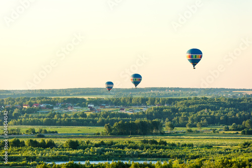 Flying in a balloon. Three balls flying on the green fields and forest.