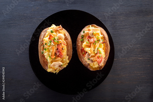 Baked potatoes with bacon and mushrooms in a rustic way on a wooden board. Close-up. Copy space. Top view