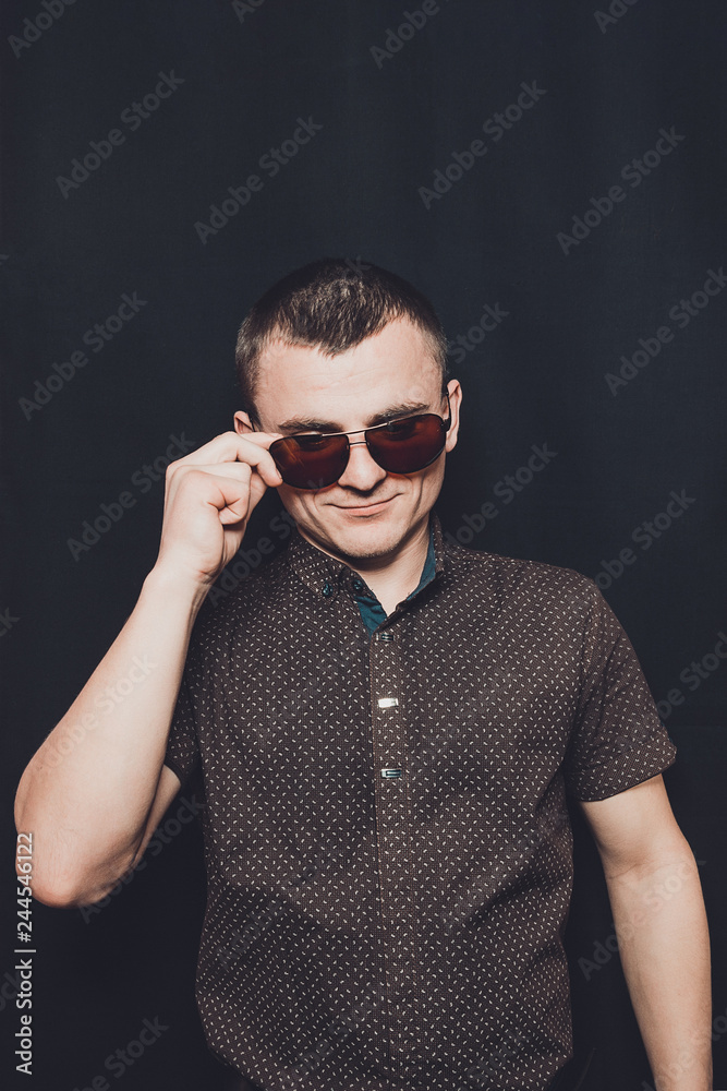 portrait of a sexy man dressed in a black shirt and brown sunglasses portrait of a sexy man dressed in a black shirt and brown sunglasses