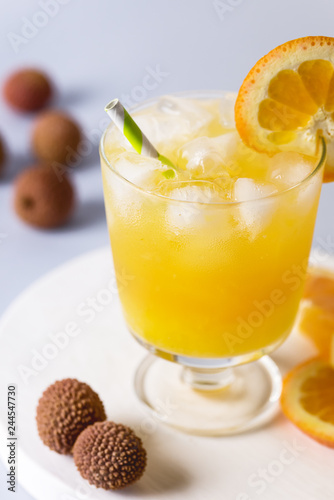 Tasty Orange Juice in Glass With Ice Cube Blue and White Background Fresh Oranges Vertical