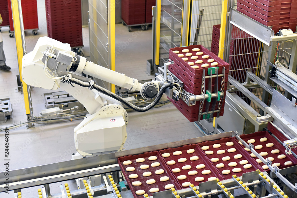 Production robot in a large bakery - Automation in the food industry // Fertigungsroboter in einer Großbäckerei - obrazy, fototapety, plakaty 