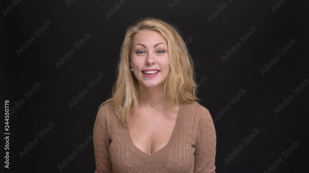 Portrait of happy caucasian long-haired woman watching joyfully into camera on black background.