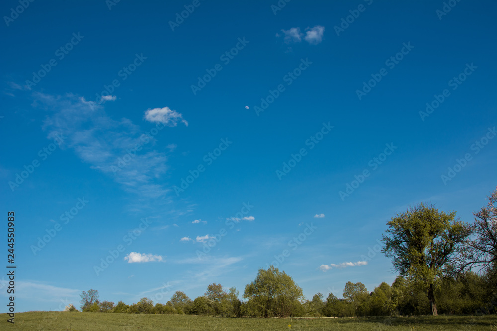 A beautiful moon on a daytime blue, magical sky with white clouds A beautiful moon on a daytime blue, magical sky with white clouds
