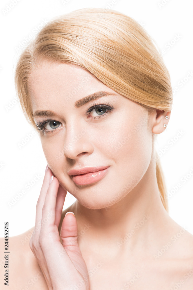 close-up view of beautiful young blonde woman touching face and looking at camera isolated on white