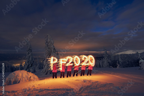 PF 2020 new year symbol drawn with sparklers by a woman in snowy landscape