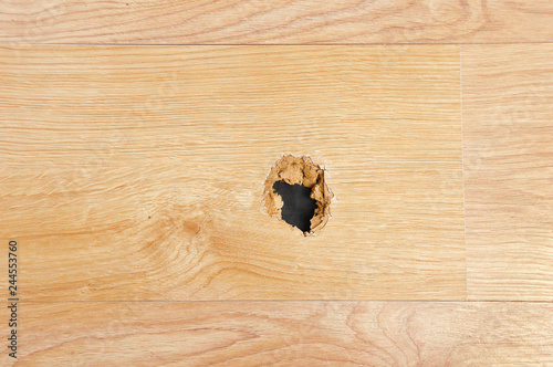 A wooden sheet floor destroyed with a hole at home