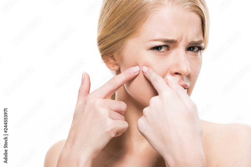 unhappy young woman squeezing pimple on face and looking at camera isolated on white unhappy young woman squeezing pimple on face and looking at camera isolated on white