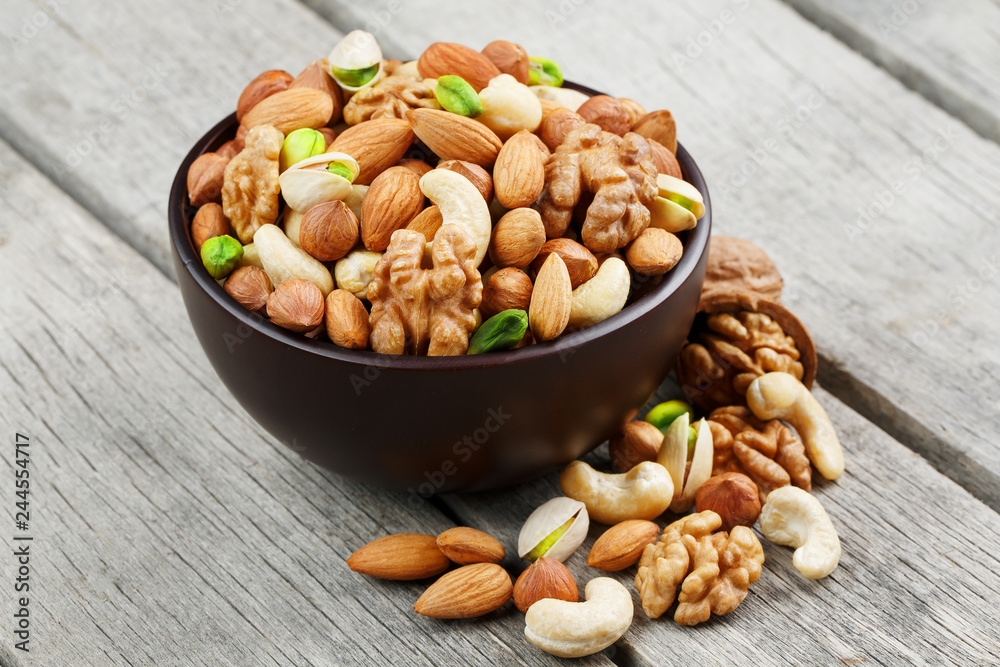 Wooden bowl with mixed nuts on a wooden gray background. Walnut, pistachios, almonds, hazelnuts and cashews, walnut. Wooden bowl with mixed nuts on a wooden gray background. Walnut, pistachios, almonds, hazelnuts and cashews, walnut.