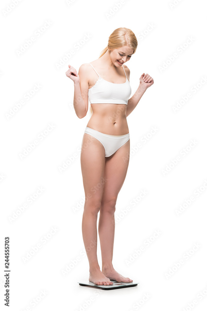 happy slim girl in underwear standing on scales and looking down isolated  on white Photos | Adobe Stock