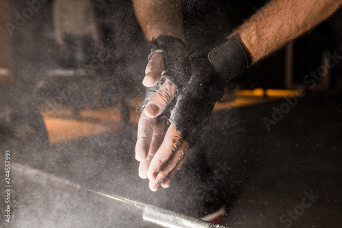 male powerlifter hand in talc and sports wristbands preparing to bench press.