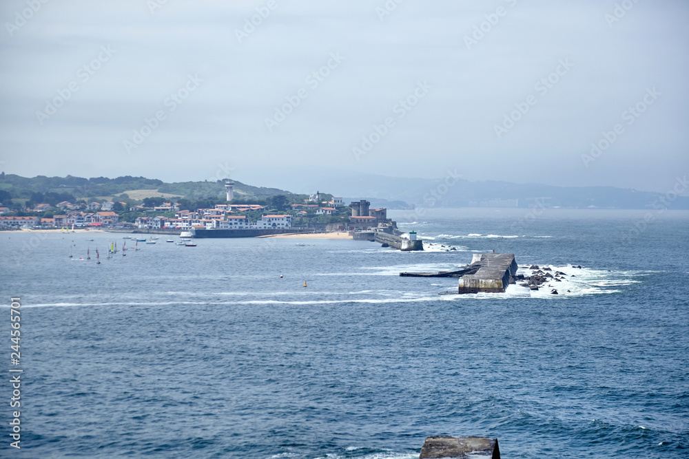 Saint Jean de Luz, France, Basque country, City views Ciboure and Castle and port of Socoa, Sailboats, Ocean waves breaking about the dam