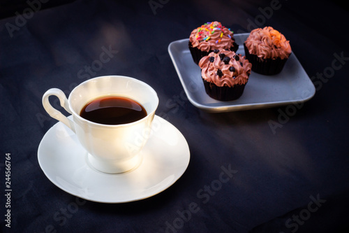 Cup of coffee served with chocolate cupcake. Sweet dessert with favorite drink.