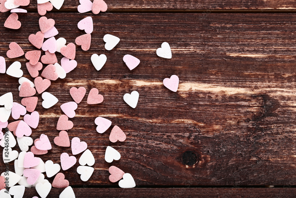 Heart shaped sprinkles on brown wooden table Heart shaped sprinkles on brown wooden table