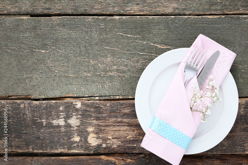 Kitchen cutlery with plate and gypsophila flowers on wooden table