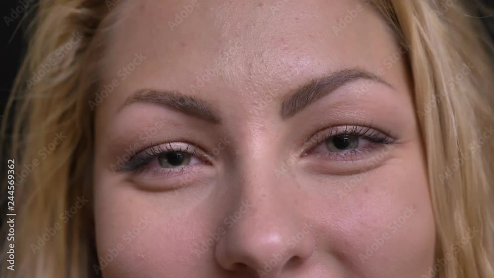 Close-up eye-portrait of caucasian long-haired woman watching smilingly into camera on black background. Close-up eye-portrait of caucasian long-haired woman watching smilingly into camera on black background.