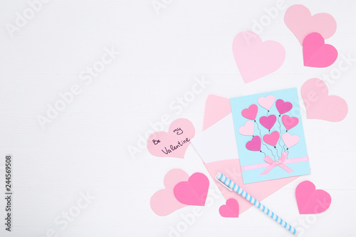 Inscription Be My Valentine with paper hearts and envelope on white background