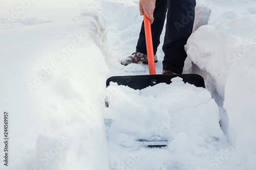 Man clearing snow by shovel after snowfall. Outdoors.