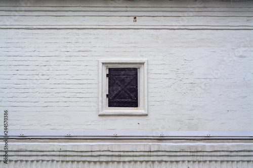 White wall of an old building with shuttered window