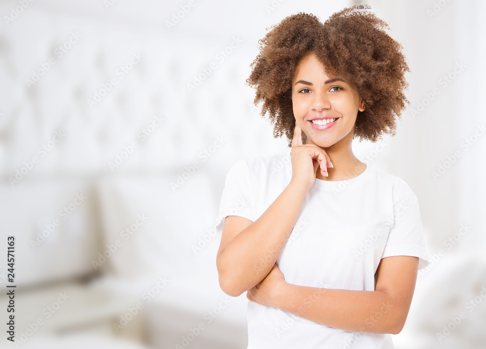 Smiling young african american woman with perfect skin care and healthy curly afro hair at home background. Blank t shirt and summer concept. Copy space Smiling young african american woman with perfect skin care and healthy curly afro hair at home background. Blank t shirt and summer concept. Copy space