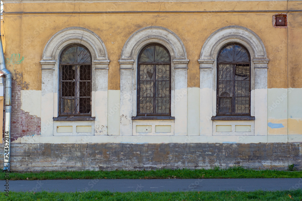 The facade of an old abandoned building with peeling paint and broken windows