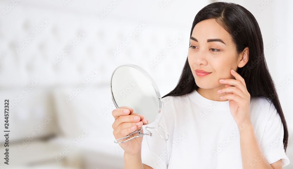 Asian woman looking in mirror at home. Macro japanese female face isolated on white background. Skin care and beauty spa concept. Anti aging and collagen. Copy space Asian woman looking in mirror at home. Macro japanese female face isolated on white background. Skin care and beauty spa concept. Anti aging and collagen. Copy space