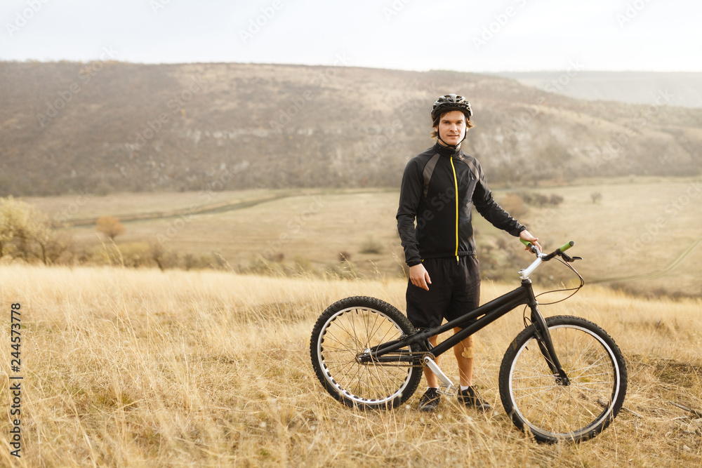 Sportsman with bicycle standing in field Sportsman with bicycle standing in field