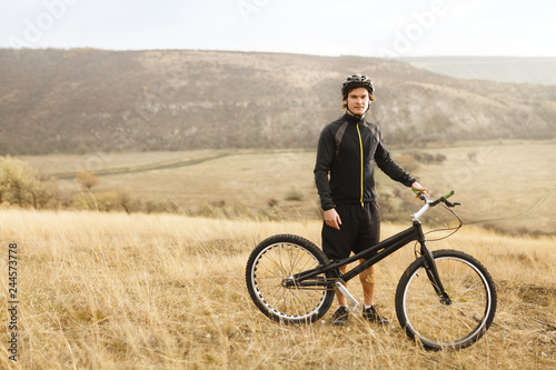 Sportsman with bicycle standing in field