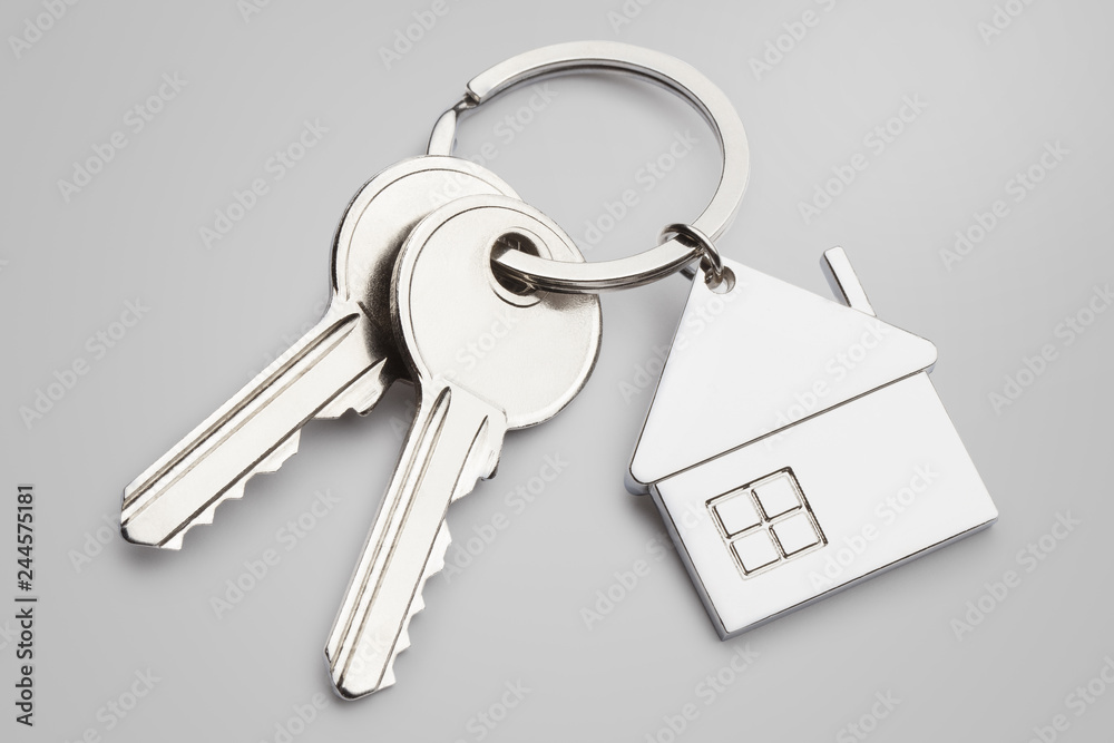 House keys with house shaped keychain on grey background House keys with house shaped keychain on grey background