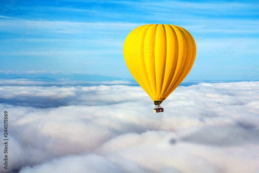 Fototapeta premium A lonely yellow hot air balloon floats above the clouds. Concept leader, success, loneliness, victory