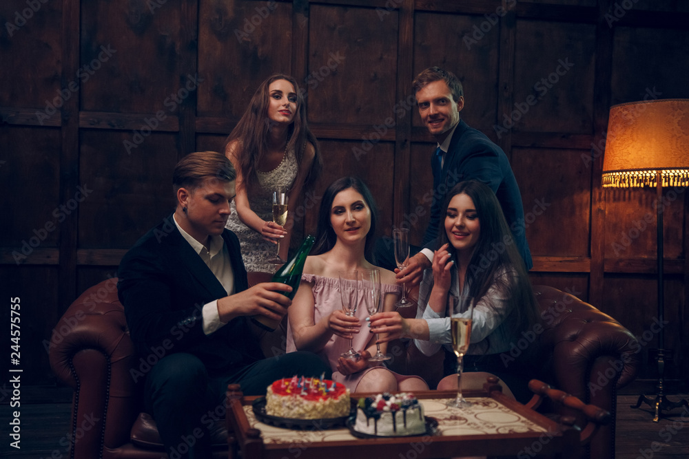 Cheerful friends celebrate birthday by drinking champagne and eating cake