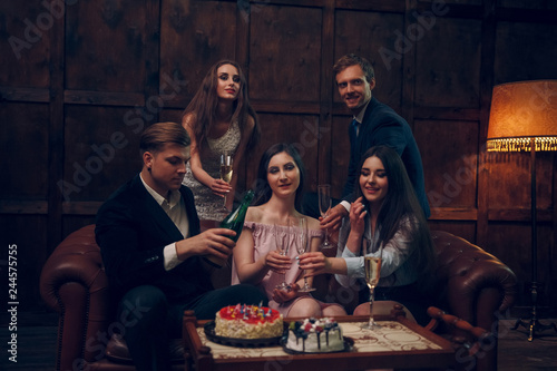 Cheerful friends celebrate birthday by drinking champagne and eating cake