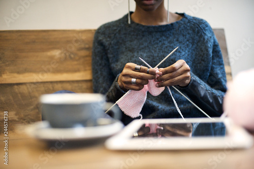 Black woman knitting in a cafe