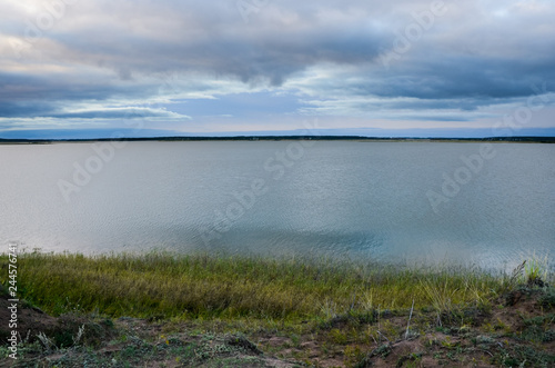 Calm lake at evening under the grey cloudy sky