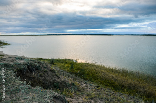 Calm lake at evening under the grey cloudy sky