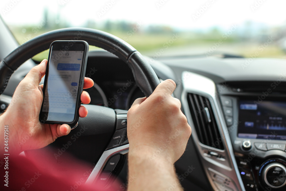 Man checking his text messages while driving. Dangerous texting in car concept.