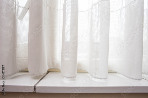 Lace curtain and windowsill close-up with sunlight