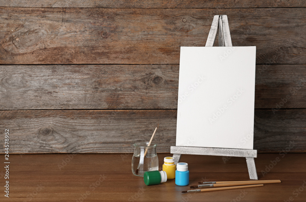 Easel with blank canvas board and painting tools for children on